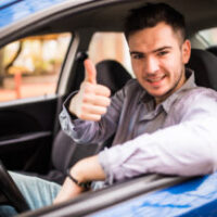 Happy smiling man sitting inside car showing thumbs up. Handsome Happy man sitting inside car showing thumbs up. Handsome guy excited about his new vehicle. Positive face expression