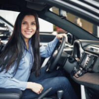auto business, car sale, consumerism and people concept - happy woman taking car key from dealer in auto show or salon auto business, car sale, consumerism and people concept - happy woman taking car key from dealer in auto show or salon.